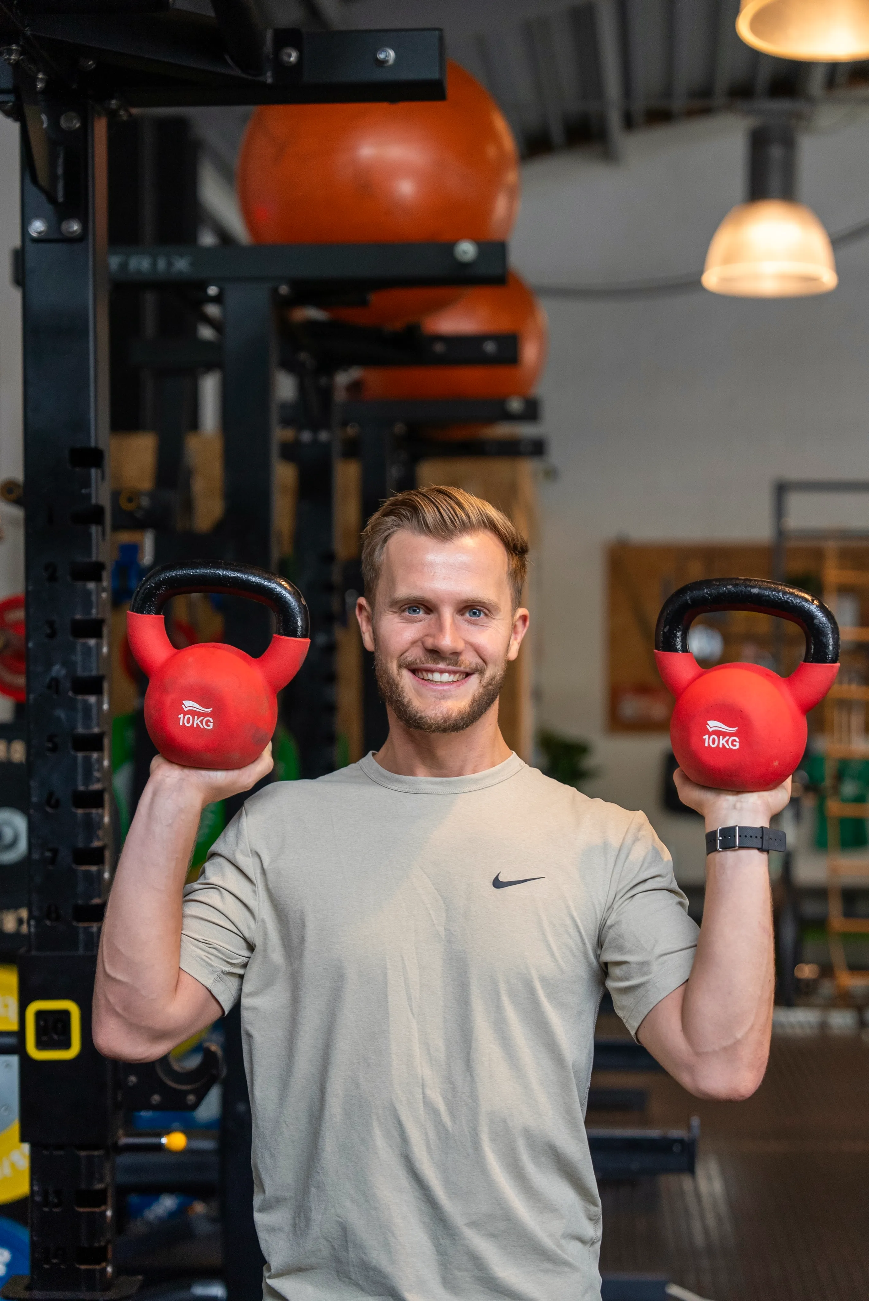 Trainer in de loods met twee rode kettlebells.